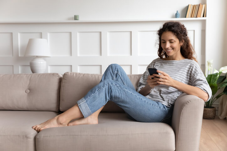 A young girl sitting on her couch comfortably while chatting with her friends using a best chat app