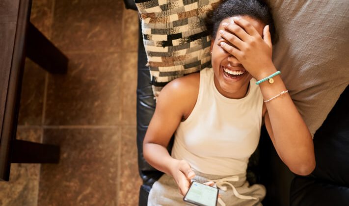 A young girl laughing while seeing a funny text message joke