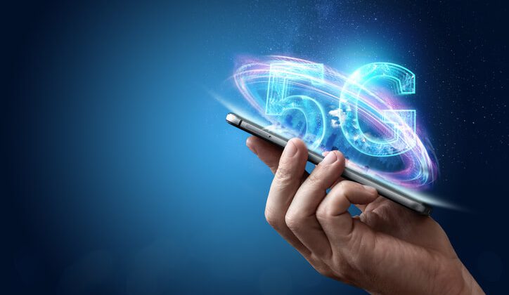 Creative background, male hand holding a phone with a 5G hologram on the background of the city.