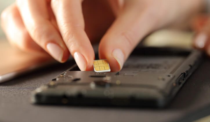 Closeup of woman hands putting sim card on smart phone
