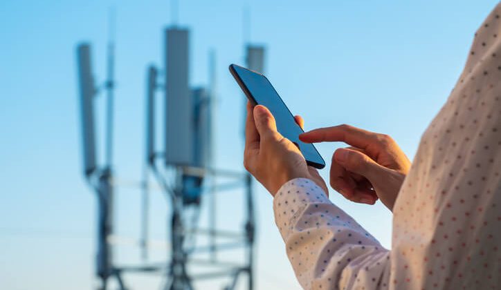 5G communications tower with man using mobile phone signal
