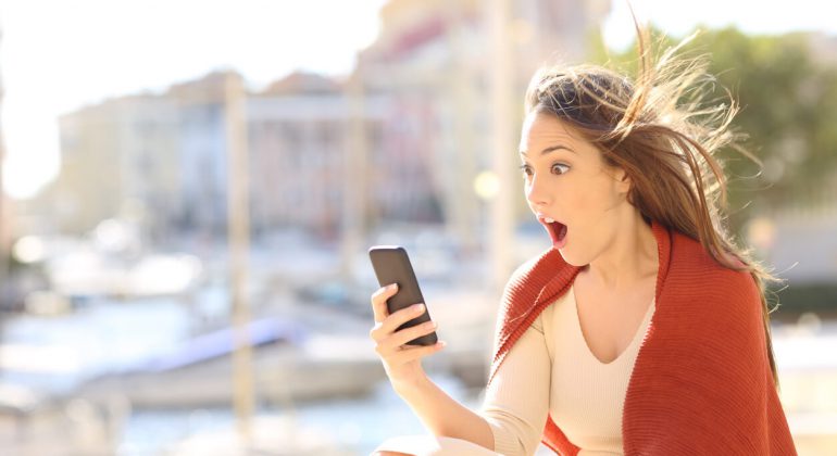 Amazed woman watching on line content about phone tips and tricks
