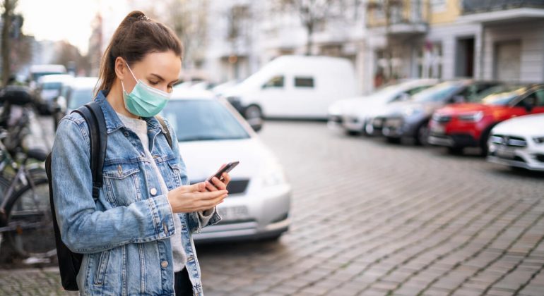 Woman wearing a protective surgical mask searchiing how to call germany