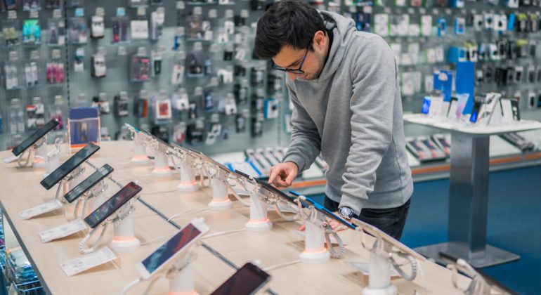 a young adult looking at phone thinking why are smartphones so expensive