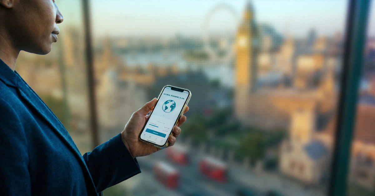 Person holding smartphone with global roaming plan on screen overlooking a city skyline